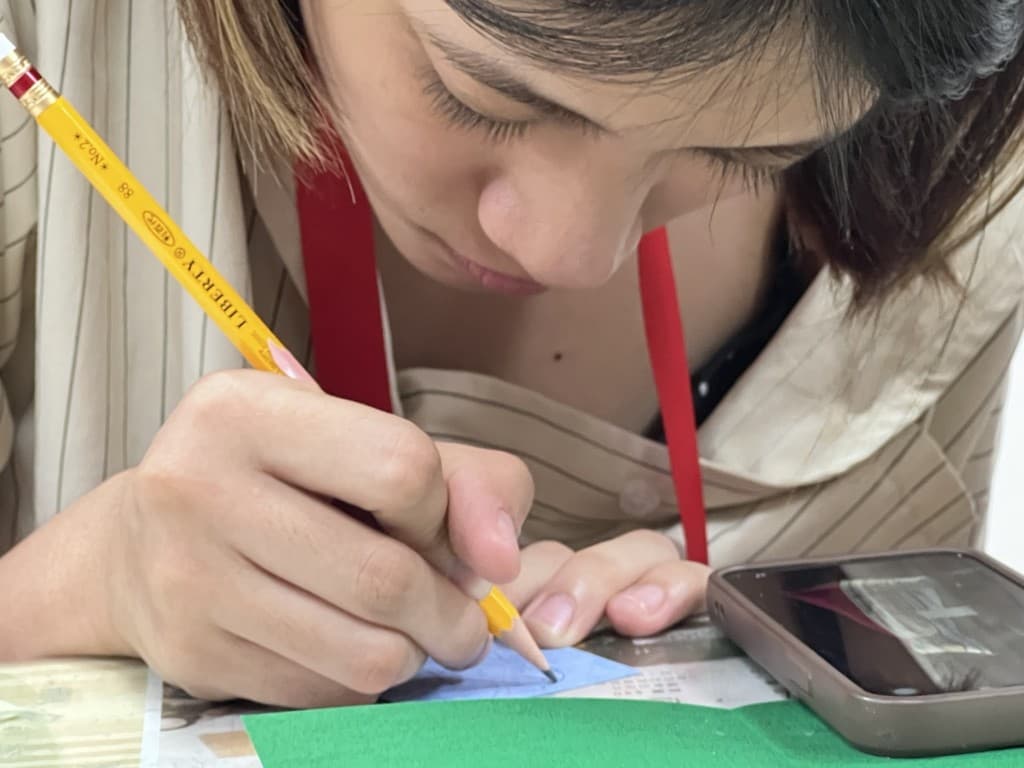 A young person drawing and writing a local story by hand.