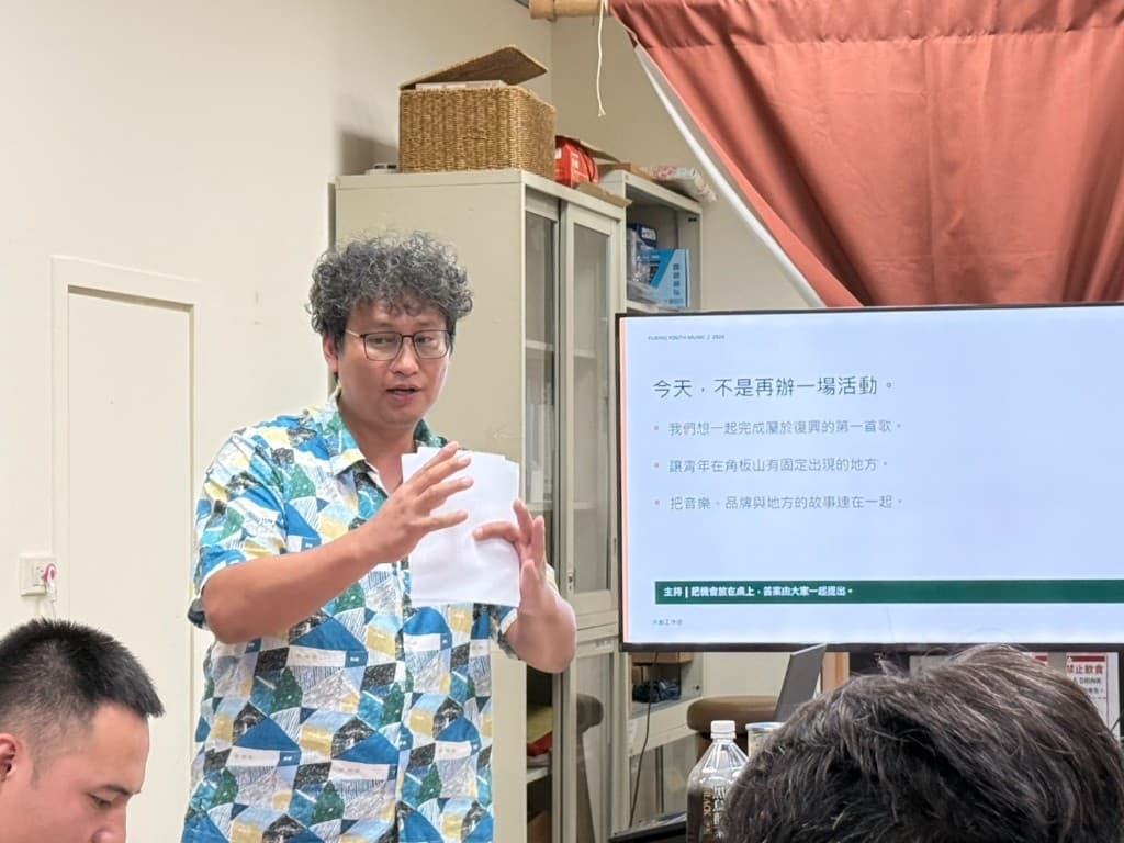 A Fuxing musician presenting beside a screen that reads: today is not about holding another event