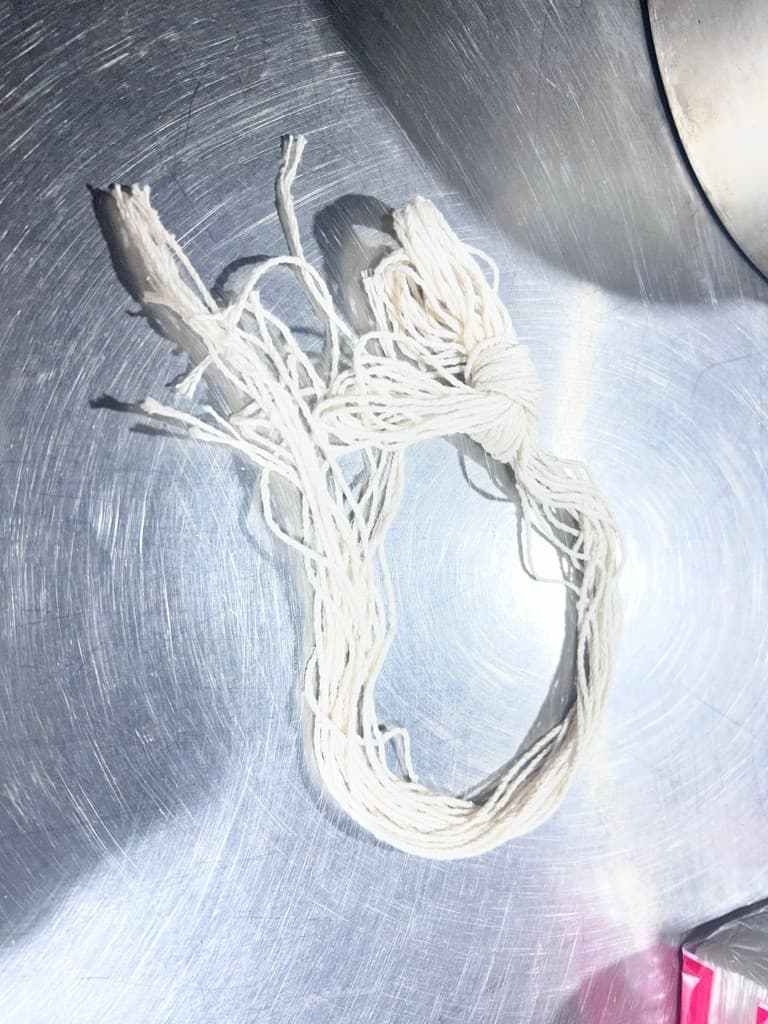A bundle of white cotton tying cord on a metal surface