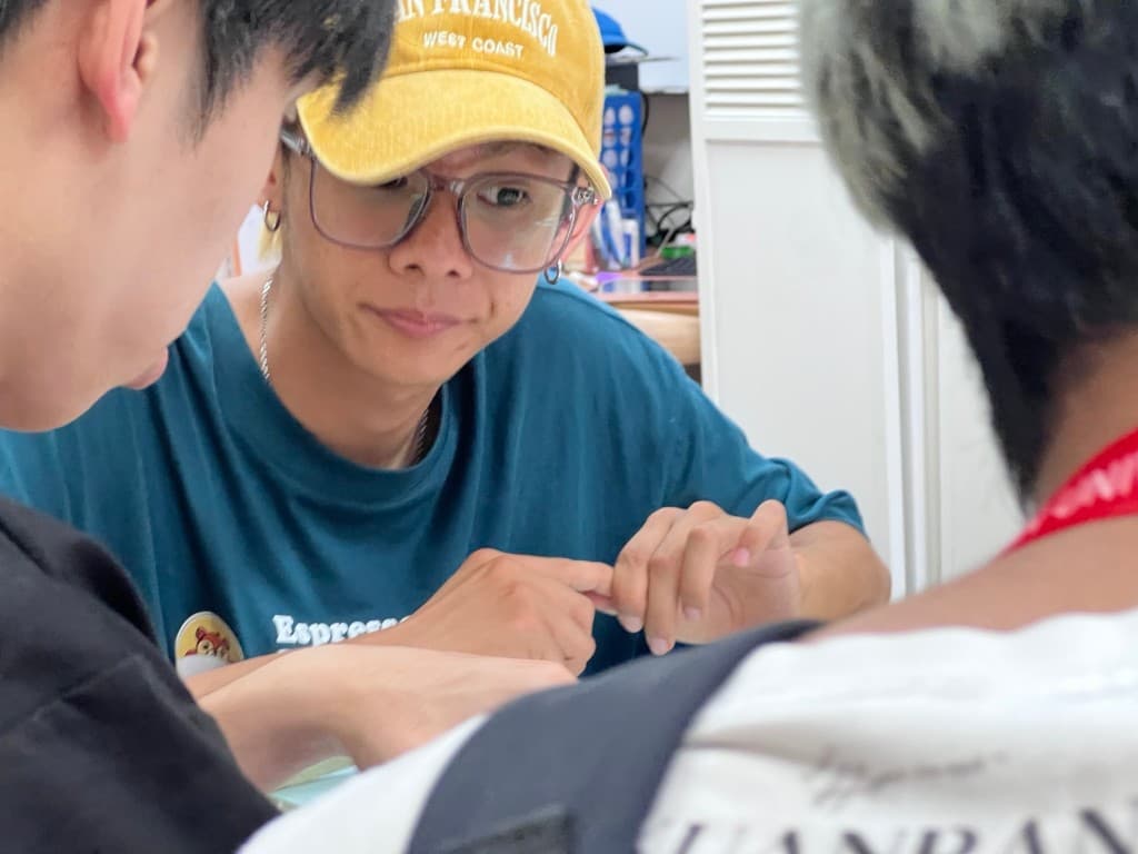 A guide in a yellow cap works closely with a student during a hands-on cultural practice