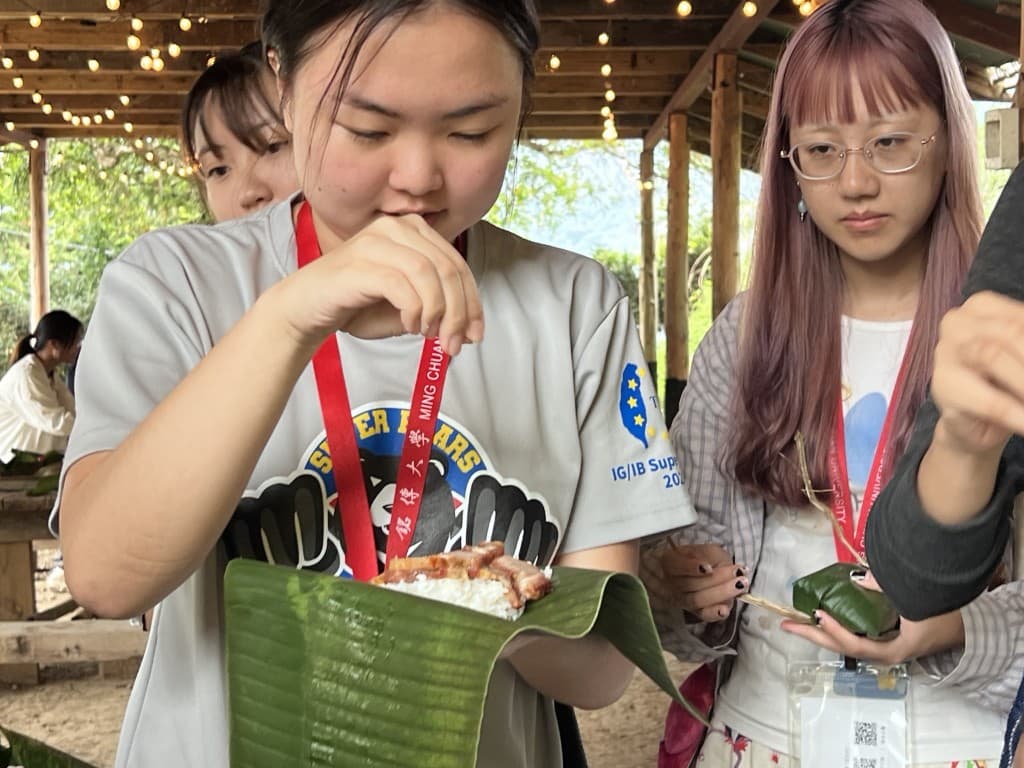A student holding a banana-leaf meal of rice and meat