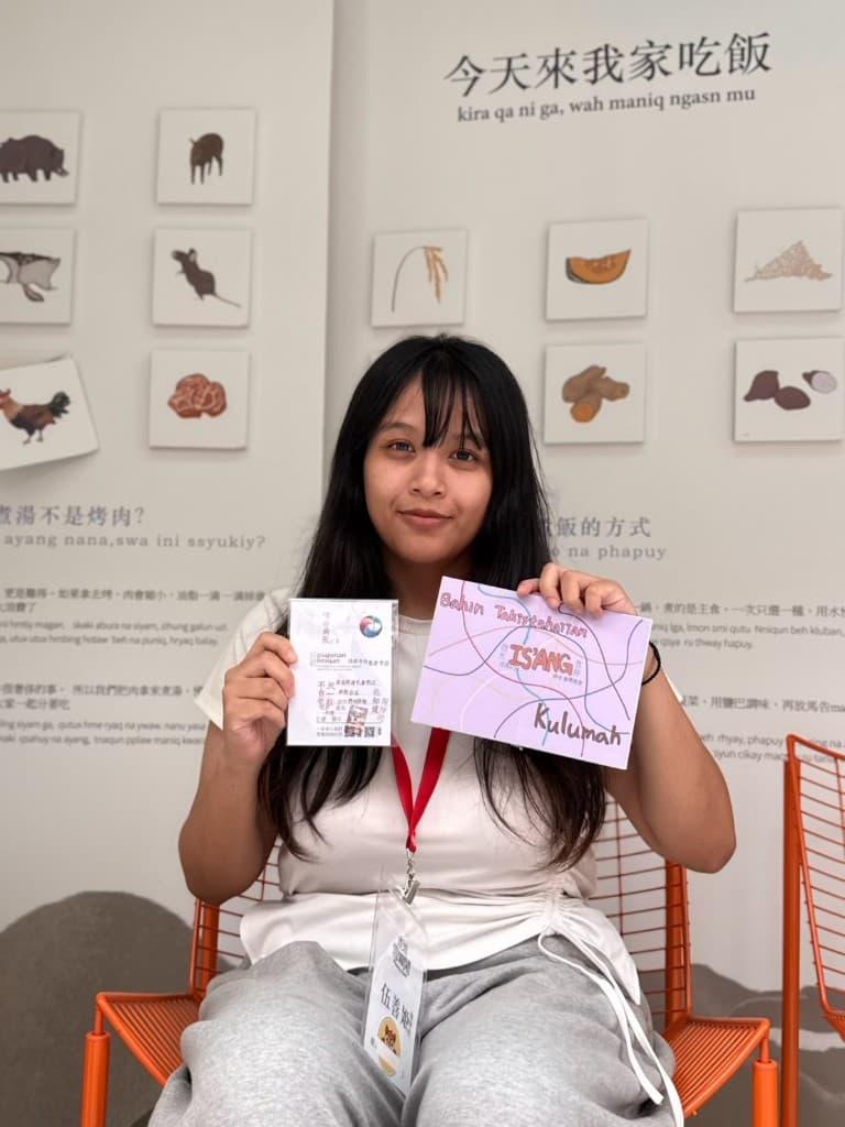 A student holding a learning card marked Bahun Takisahatan, ISIANG and Kulumah